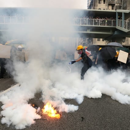 An anti-government protester tries to extinguish tear gas during a clash with riot police in Hong Kong on Saturday. Photo: Sam Tsang