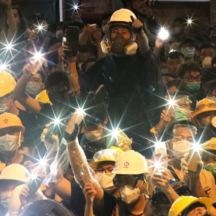 Protestors raise up their mobile flashlights outside police headquarters in Wan Chai. Photo: Felix Wong