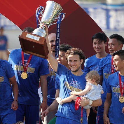 Diego Forlan lifts the Hong Kong Premier League trophy while carrying baby daughter Luz, while his son Martin looks on in May 2018. Photo: Winson Wong