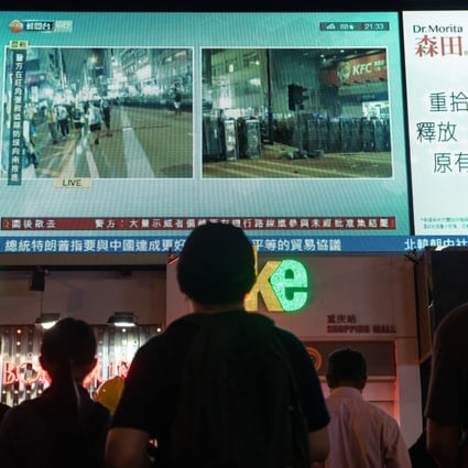 People in Tsim Sha Tsui watch a live television broadcast of protests in the city on August 3. Photo: Bloomberg