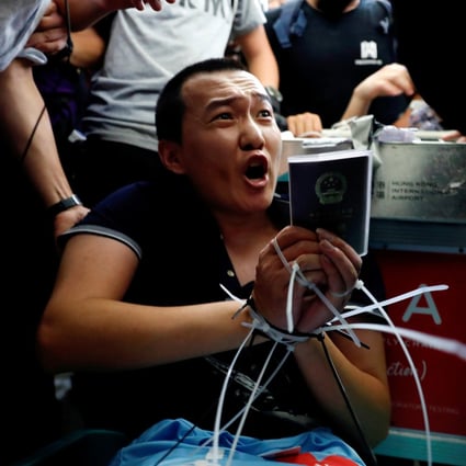 Fu Guohao is surrounded by protesters after having his hands tied together at Hong Kong International Airport. Photo: Reuters