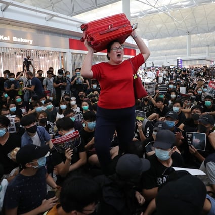 A woman attempts to navigate through a crowd of anti-government protesters inside the departure hall of Hong Kong International Airport, on Monday. The protests forced the cancellation of hundreds of flights over two days. Photo: Sam Tsang