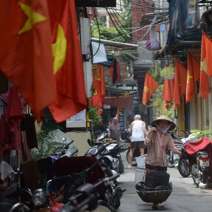 A street vendor walking past rows of Vietnamese national flags hung in front of homes for Vietnam's National Day in downtown Hanoi. Photo: AFP