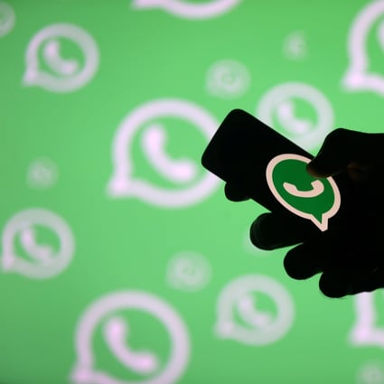 A man poses with a smartphone in front of a displayed Whatsapp logo in this illustration. Photo: Reuters