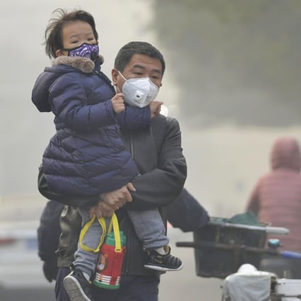 A man and his daughter wear face masks to protest themselves from air pollution in Beijing. Photo: Kyodo