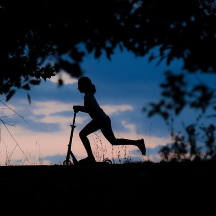 A child rides a scooter at dusk in a park in Bucharest, Romania. Photo: AP