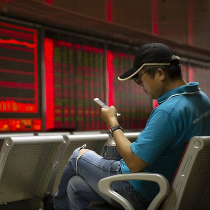 A Chinese investor uses his smartphone as he monitors stock prices at a brokerage house in Beijing on August 20, 2019. Photo: Associated Press