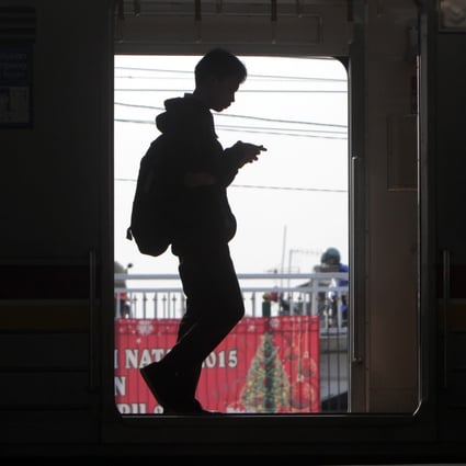 A commuter looking at his mobile phone in Jakarta, Indonesia. Photo: EPA