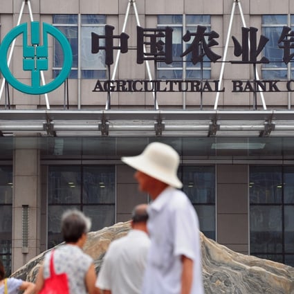 People walk past the headquarters of the Agricultural Bank of China in Beijing. New loans growth in China declined in August. Photo: AFP