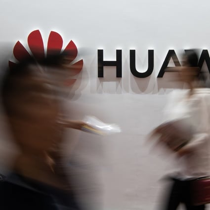 People walk past a Huawei logo during the Consumer Electronics Expo in Beijing. Photo: AFP