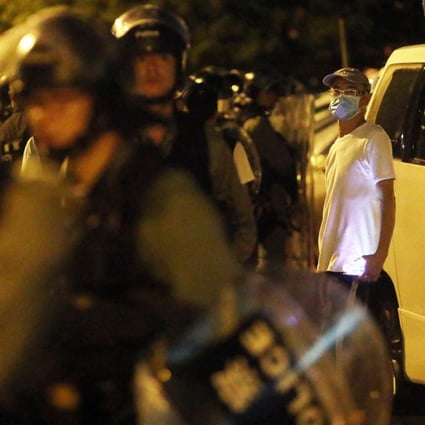 A white-shirted man stands behind riot police in Yuen Long on the night of July 21. Police have been accused of neglected their duties by being slow in responding to that night’s attack on protesters and commuters by armed men. Photo: Winson Wong