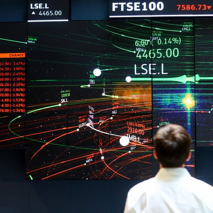 An employee looks at information for the FTSE 100 share price information in the atrium of the London Stock Exchange Group Plc's offices on July 6, 2018. Photo: Bloomberg