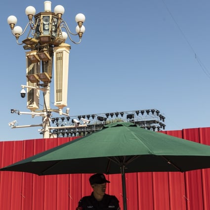 A security guard stands near surveillance cameras on a lamp post at Tiananmen Square in Beijing. Photo: Bloomberg
