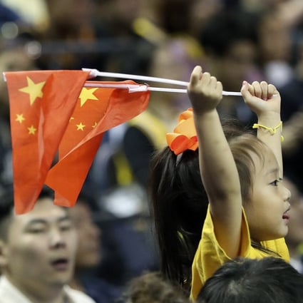 A child holds up two Chinese national flags as she watches a pre-season NBA basketball game between the Brooklyn Nets and Los Angeles Lakers at the Mercedes Benz Arena in Shanghai on October 10. Photo: AP
