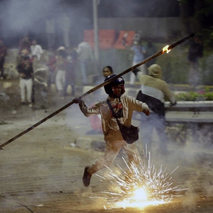 A student protester throws a burning stick at riot police during a clash in Jakarta on September 30. Photo: AP