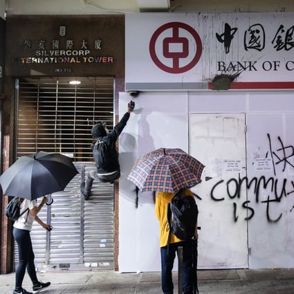 Demonstrators spray paint a security camera at a Mong Kok branch of the Bank of China. Photo: Bloomberg