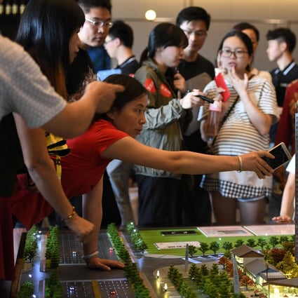 A China Vanke’s sales agent explains the attraction of its housing project to visitors at a showroom during the National Day "Golden Week" holiday, in Dongguan, Guangdong province. Photo: Reuters