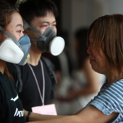 A woman cries for anti-government protesters as they hand out face masks to local residents, outside Kwai Fong MTR station on August 12. Riot police had fired tear gas in the area the night before. Photo: Winson Wong