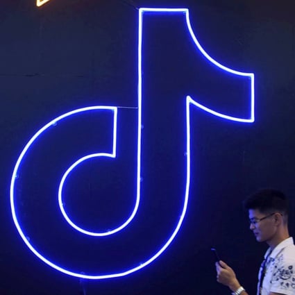 A man holding a phone walks past a sign with the TikTok logo at the International Artificial Products Expo in Hangzhou in October. Photo: Reuters