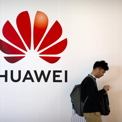 A man uses his smartphone as he stands near a billboard for Chinese technology firm Huawei at the PT Expo in Beijing, Thursday, Oct. 31, 2019. Photo: AP.