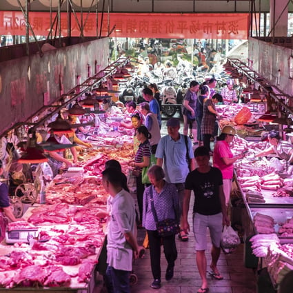 Customers walk past pork stalls at the Dancun Market in Nanning, Guangxi province. Photo: Bloomberg