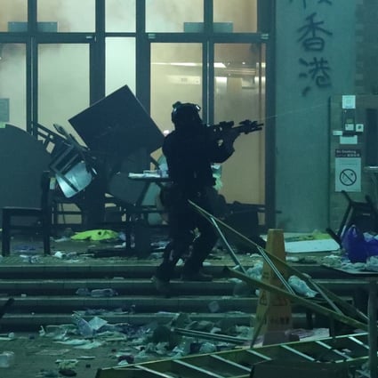 A police officer carrying a SIG516 assault rifle attempts to enter the Polytechnic University campus in Hung Hom on Monday morning. Photo: Sam Tsang