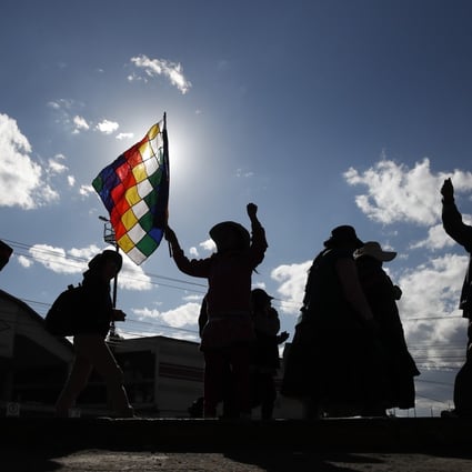 A supporter of former President Evo Morales waves a Whipala flag as he blocks the highway to access the "Yacimientos Petroliferos Fiscales Bolivianos" plant in El Alto, Bolivia. Photo: AP Photo