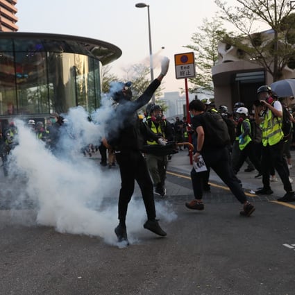 A masked protester throws back a round of tear gas. Photo: Sam Tsang