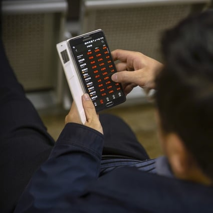 A Chinese investor uses a smartphone to monitors stock prices at a brokerage house in Beijing. Photo: Associated Press