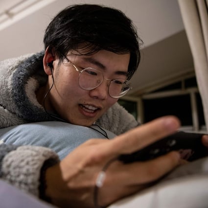 Zhuansun Xu, 22, talking to a girlfriend on his phone while playing a mobile game in his room in Beijing. A foreign exchange trader by day, he is a “virtual boyfriend” by night, chatting with female clients. Photo: AFP