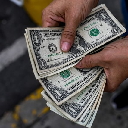 A street hawker counts dollar bills in Caracas, Venezuela, on November 19. In Venezuela, the US dollar is used for most transactions after years of hyperinflation and devaluation of the bolívar. Photo: AFP