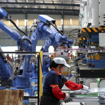 A worker assembles air conditioner's components next to the robot arms at a factory in Suixi county in central China's Anhui province in 2018. Photo: AP