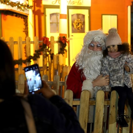 A child takes a picture with a man dressed as Santa Claus at a Christmas market in Lisbon, Portugal, on December 22. Photo: Xinhua