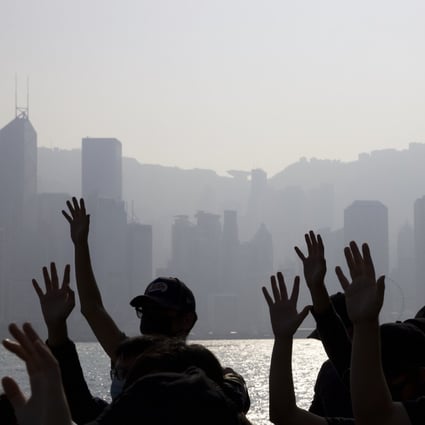 Pro-democracy protesters raise their hands to symbolise the five demands of their movement, with the Hong Kong Island skyline behind them. Photo: AP