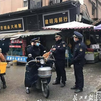 Law enforcement officers stand guard outside the seafood market in Wuhan that was ordered to close after a mystery flu outbreak. Photo: Yangtze Daily
