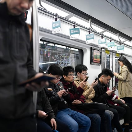 Commuters use their mobile phones as they ride on a subway in Beijing. Photo: AFP
