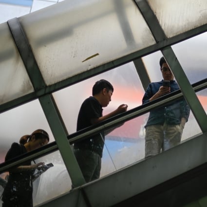Pedestrians check their smartphones as they ride an escalator to cross an overpass in Beijing on June 13, 2019. A handful of Chinese internet players control swathes of online businesses from retail and entertainment to social media and financial services. Photo: Agence France-Presse