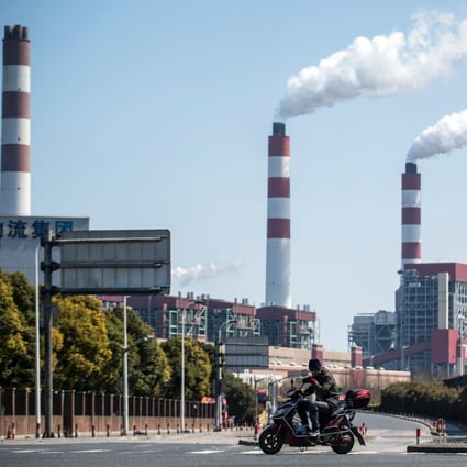 A man rides his scooter near the a coal power plant in Shanghai. Photo: AFP