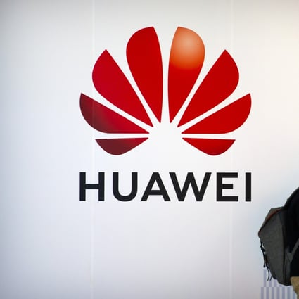 A man uses his smartphone as he stands near a billboard for Chinese technology firm Huawei at the PT Expo in Beijing, 2020. Photo: AP