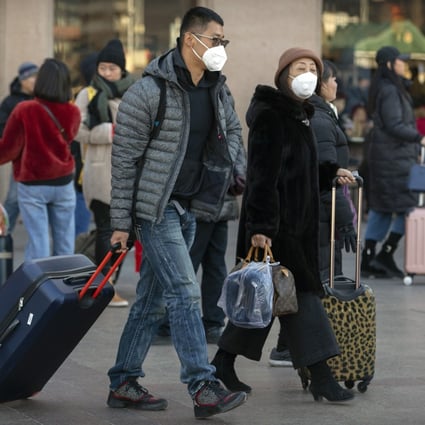 Travellers wear face masks as they walk outside the Beijing Railway Station. Photo: AP Photo