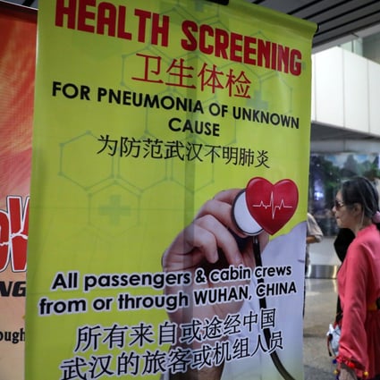 Passengers pass a banner about the Wuhan coronavirus at a thermal screening point in the international arrival terminal of Kuala Lumpur International Airport in Malaysia on Tuesday. Photo: Reuters