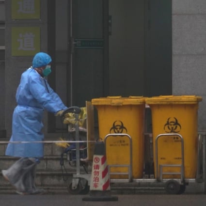 Staff move bio-waste containers past the entrance of the Wuhan Medical Treatment Centre in China, where some people infected with the new virus are being treated. Photo: AP