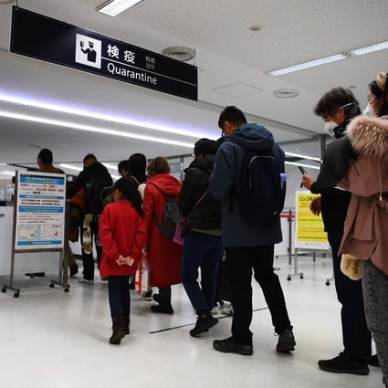 Passengers arriving from Wuhan pass through a health screening station at Narita airport in Tokyo on Thursday. Photo: AFP