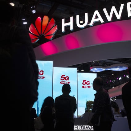 Attendees walk past a display for 5G services from Chinese technology firm Huawei at the PT Expo in Beijing, 2019. Photo: AP