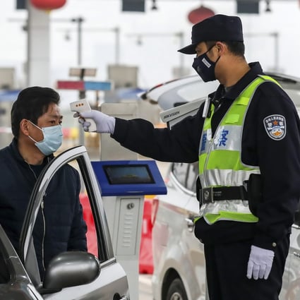 A policeman uses a digital thermometer to take a driver's temperature at a checkpoint in Wuhan, epicentre of the coronavirus outbreak. Photo: AP