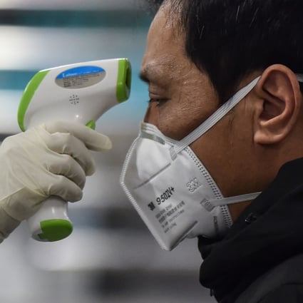A medical worker checks the temperature of a Wuhan resident as scientists rush to develop a vaccine for the coronavirus in China. Photo: AFP