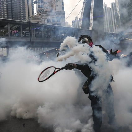 An anti-government protester uses a tennis racquet to return a canister fired by police during a clash in Tsuen Wan in August. Photo: Sam Tsang