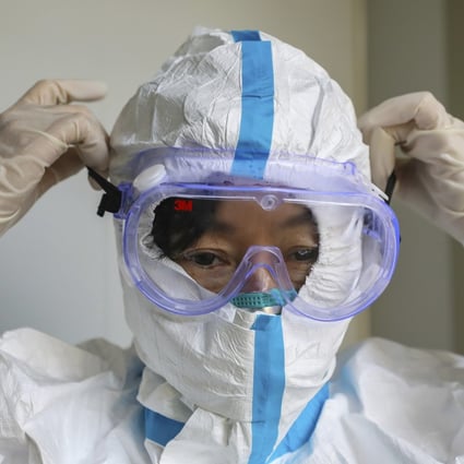 A doctor puts on a protective suit and goggles at a hospital in Wuhan. Photo: AP