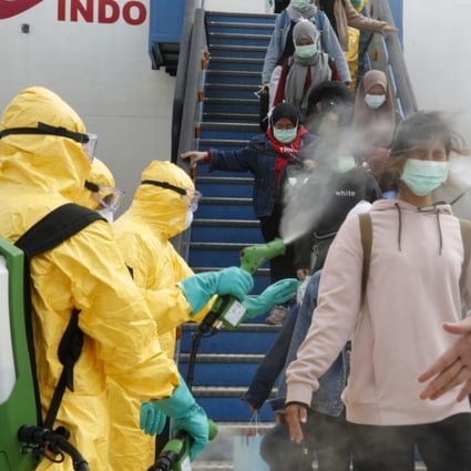 Medical officers spray Indonesian nationals with antiseptic after they arrived from Wuhan, China centre of the coronavirus epidemic. Photo: Reuters