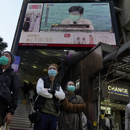 People wearing protective face masks stand in front of a screen broadcasting a speech by Hong Kong Chief Executive Carrie Lam on January 31. Photo: AP